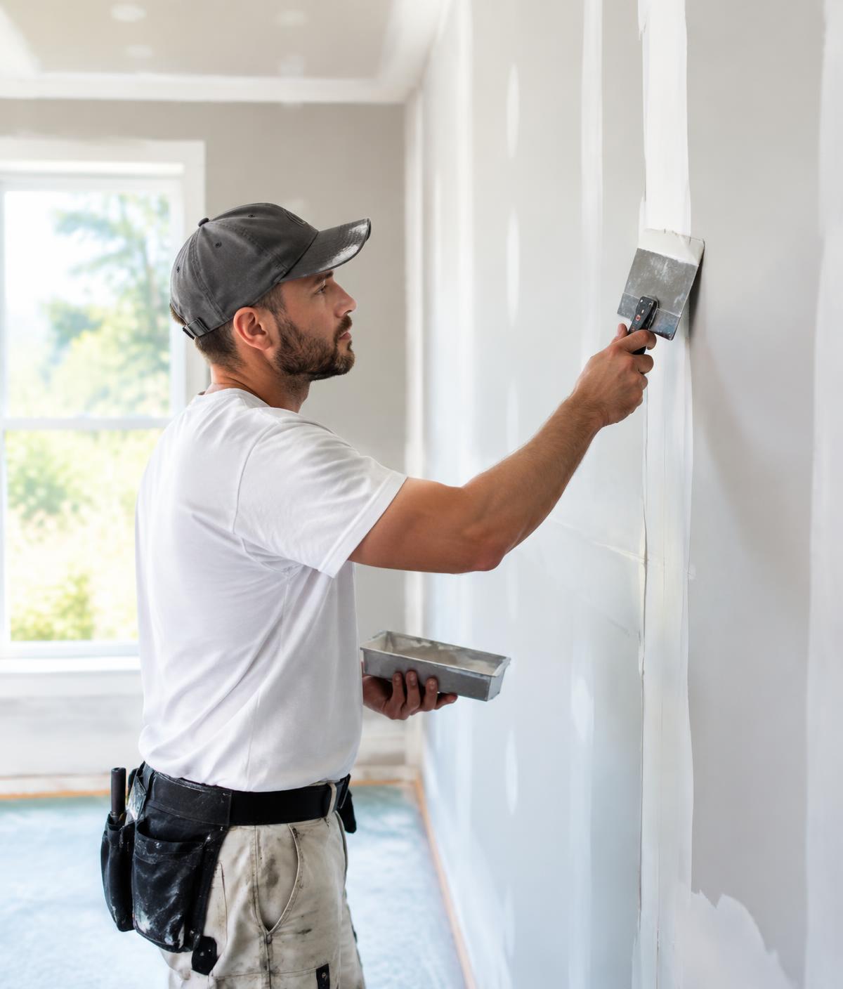 Contractor finishing drywall seams in a residential room